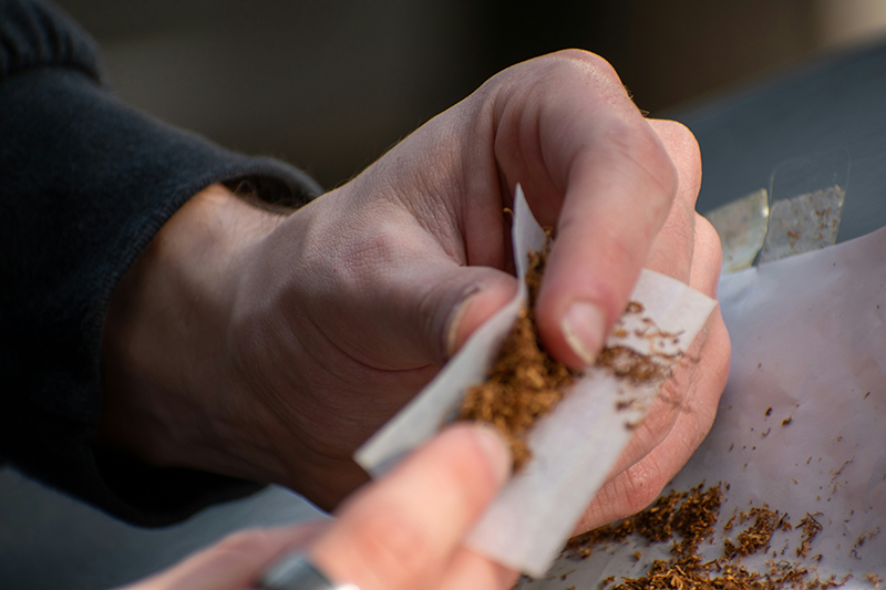A man rolls tobacco into a cigarette. The Master Tobacco settlement in the late 90’s is one of the largest class action claims in United States history, resulting in billions paid out to Medicare and Medicaid over decades.