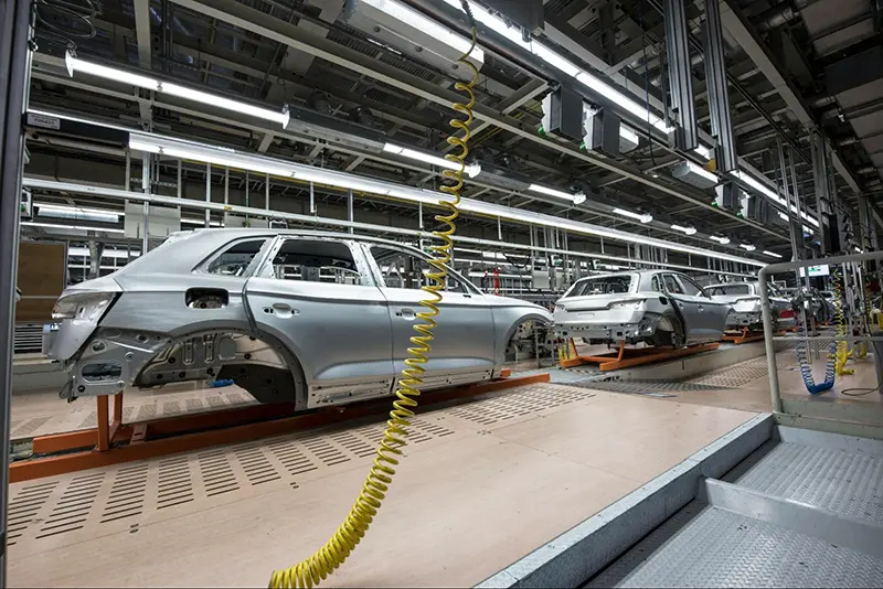 An automobile manufacturing assembly line with partially assembled car frames on conveyor systems. The production process highlights the importance of quality control in preventing defects. A product liability lawyer may handle cases involving a product liability lawsuit due to manufacturing defect claims if a faulty vehicle part causes harm to consumers. Ensuring rigorous testing and adherence to safety standards is crucial in avoiding legal disputes.